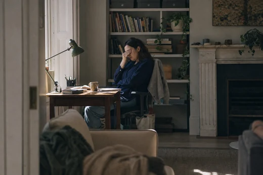 A woman slumped at a desk in flat late-afternoon light.