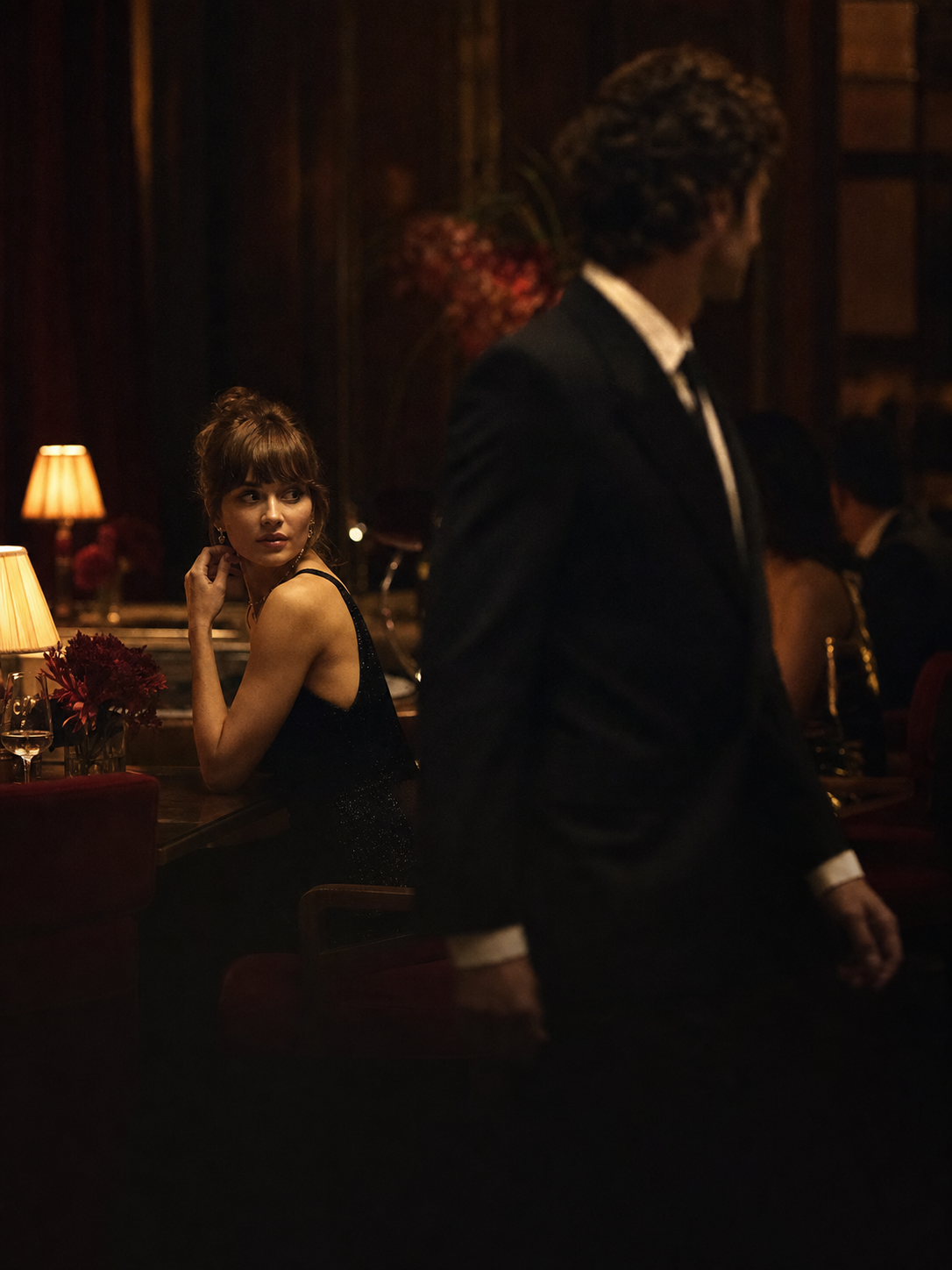 A woman notices a sharply dressed man as he passes in an intimate restaurant